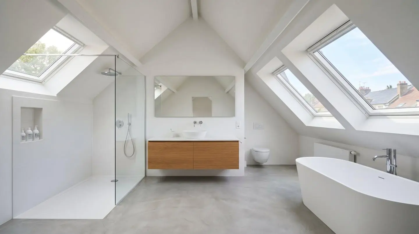 Vue grand angle d'un grenier aménagé moderne avec salle d'eau sous pente, lumineux avec lumière naturelle venant d'un velux