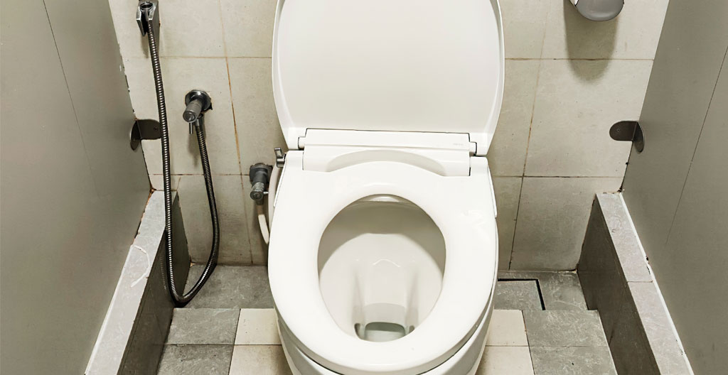 Gros plan sur un tuyau d'évacuation PVC blanc de petit diamètre avec raccord installé le long d'un mur moderne